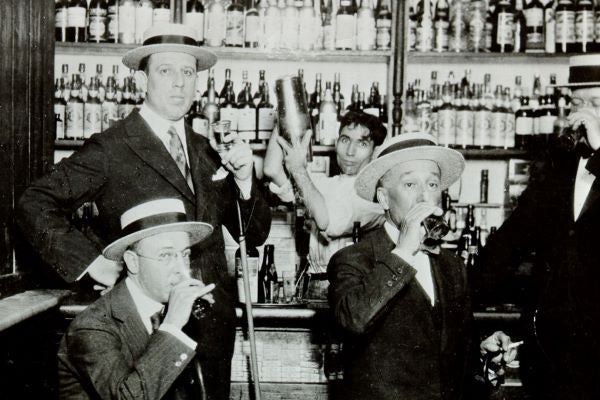 Prohibition-era speakeasy bar scene with bartenders and patrons - 1933 Liquor Co